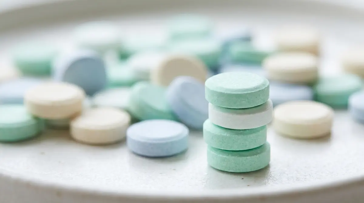 Pastel-colored chewable tablets scattered on a white surface with one stack in sharp focus